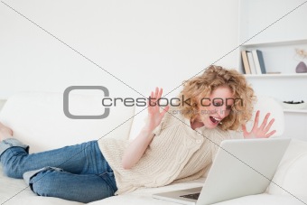 Beautiful blonde woman relaxing with her laptop while lying on a