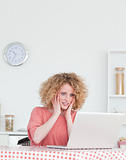 Pretty blonde female relaxing with her laptop while sitting in t