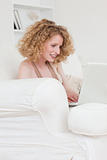 Cute blonde female relaxing with her laptop while sitting on a s