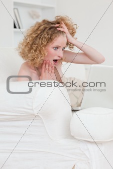 Cheerful blonde female relaxing with her laptop while sitting on