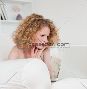 Pretty blonde female relaxing with her laptop while sitting on a