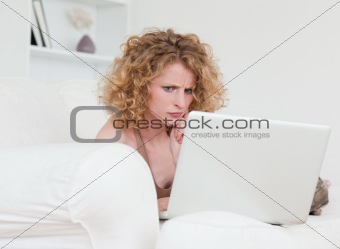 Upset blonde female relaxing with her laptop while sitting on a 