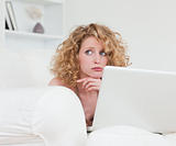 Lovely anxious female relaxing with her laptop while sitting on 