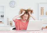 Upset blonde female relaxing with her laptop while sitting in th
