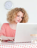 Attractive blonde woman relaxing with her laptop while sitting i