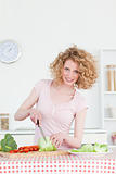 Beautiful blonde woman cooking some vegetables in the kitchen