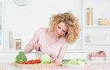 Charming blonde woman cooking some vegetables in the kitchen