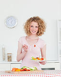 Attractive blonde woman eating some vegetables in the kitchen