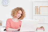 Charming blonde woman relaxing with her laptop while sitting in 