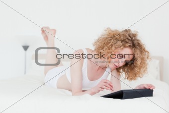 Charming blonde woman relaxing with her tablet while lying on a 