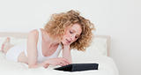 Good looking blonde woman relaxing with her tablet while lying o