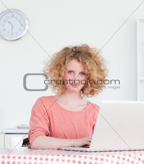Gorgeous blonde woman relaxing with her laptop while sitting in 