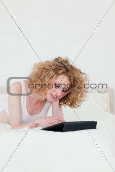 Attractive blonde woman relaxing with her tablet while lying on 