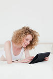 Pretty blonde woman relaxing with her tablet while lying on a be