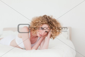 Attractive blonde woman relaxing while lying on her bed