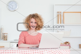 Lovely blonde woman relaxing with her laptop while sitting in th