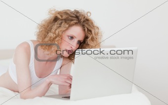 Beautiful blonde woman relaxing with her laptop while lying on h