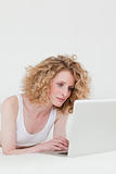 Cute blonde woman relaxing with her laptop while lying on her be