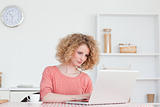 Cute blonde woman relaxing with her laptop while sitting in the 
