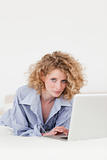 Good looking blonde female relaxing with her laptop while lying 