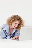Pretty blonde female relaxing with her laptop while lying on her
