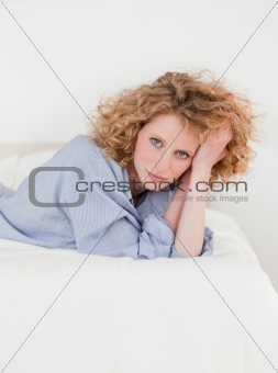 Charming blonde woman posing while lying on her bed
