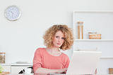 Pretty blonde woman relaxing with her laptop while sitting in th
