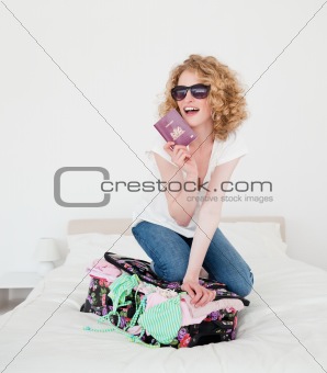 Beautiful blonde female trying to close her suitcase in her bedr