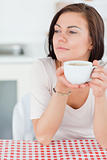 Portrait of a smiling dark-haired woman having a coffee