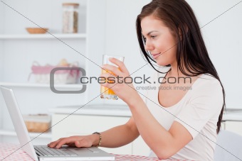 Close up of a woman using her laptop and drinking juice