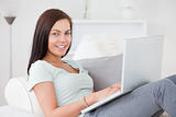 Beautiful woman typing on her laptop while sitting on her sofa
