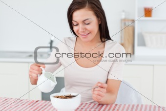 Brunette pouring milk in her cereal