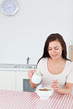Portrait of a smiling woman pouring milk in her cereal