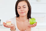 Close up of a cute brunette with an apple and a piece of cake