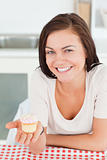 Laughing brunette showing a cupcake