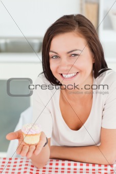 Laughing brunette showing a cupcake