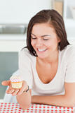 Laughing brunette looking at a cupcake