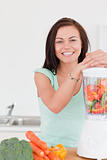 Charming dark haired woman posing with a blender