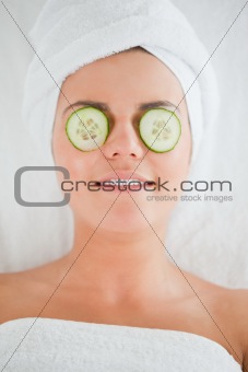 Smiling woman with cucumber slices on the face
