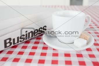 A cup of tea and a newspaper on a tablecloth