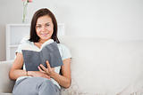 Cute dark-haired woman holding a book while looking at the camer