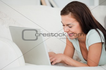 Close up of a young brunette on a sofa using a laptop