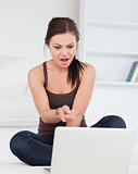 Surprised dark-haired woman using her laptop
