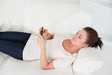 Young brunette texting while lying on her sofa