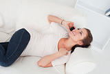 Cute brunette calling while lying on her sofa