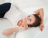 Close up of a smiling brunette calling while lying on her sofa