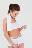 Fit woman with a towel on her shoulders measuring her belly