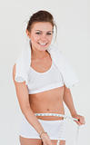 Athletic brunette with a towel measuring her belly