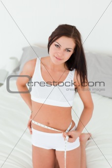 Young woman measuring her belly