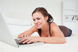Cute woman lying on a carpet with a laptop